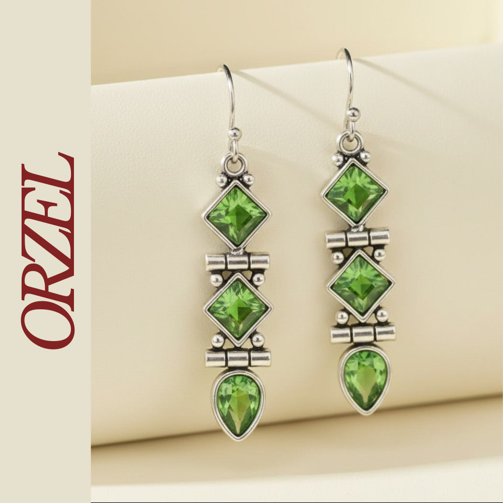 Boucles d’oreilles pendantes argentées avec pierres vertes géométriques.