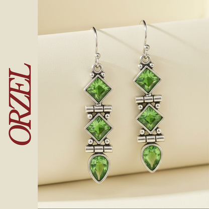 Boucles d’oreilles pendantes argentées avec pierres vertes géométriques.