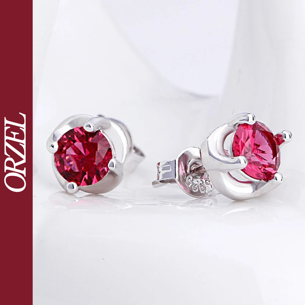 Boucles d’oreilles clous argentées avec pierre rouge.