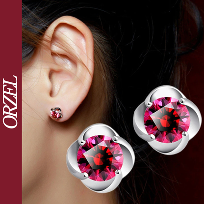 Boucles d’oreilles clous argentées avec pierre rouge.